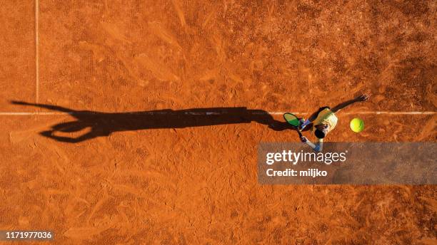 tennis speler op service op gravel court - taking a shot sport stockfoto's en -beelden