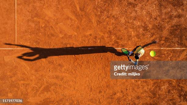 tennis player on service on clay court - tennis stock pictures, royalty-free photos & images