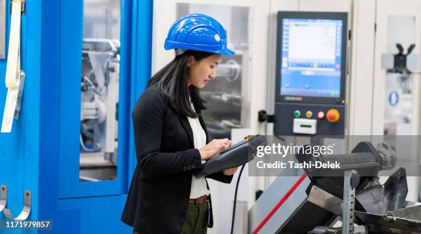 ingeniero femenino que utiliza un sistema de control remoto de fábrica - remote controlled fotografías e imágenes de stock