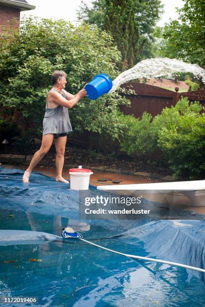 man hauls water from a flooded pool cover - flood cleanup stock pictures, royalty-free photos & images