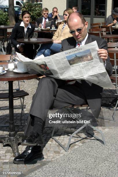 Mann liesst die Berufswelt DIE WELT Stellenmarkt sitzt im Cafe Kaffee Strassencafe