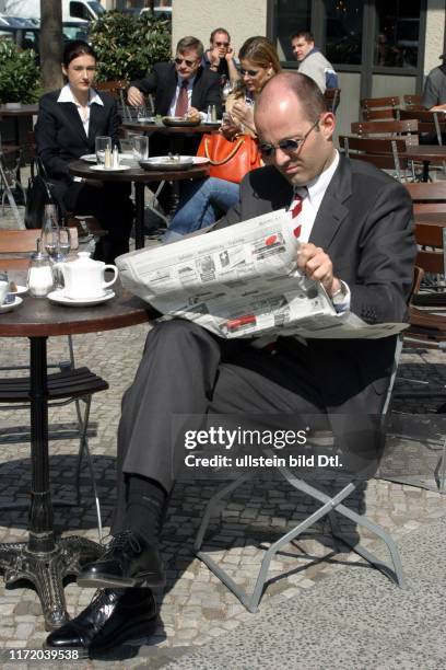 Mann liesst die Berufswelt DIE WELT Stellenmarkt sitzt im Cafe Kaffee Strassencafe