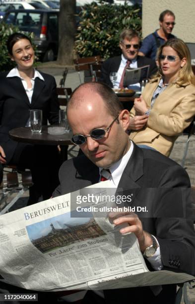Mann liesst die Berufswelt DIE WELT Stellenmarkt sitzt im Cafe Kaffee Strassencafe