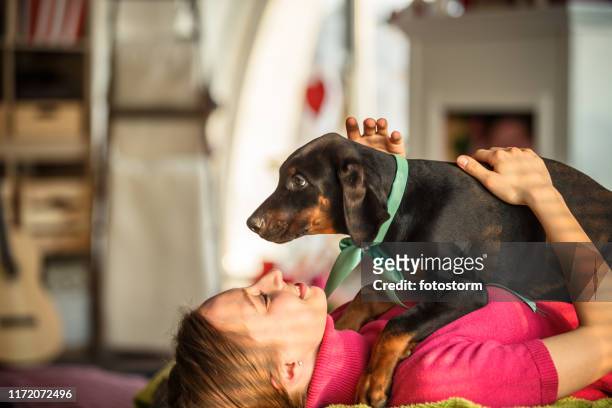 cheerful young woman cuddling her cute doberman puppy - white doberman pinscher stock pictures, royalty-free photos & images