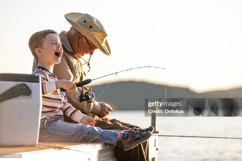 Pesca do avô e do neto no por do sol no verão