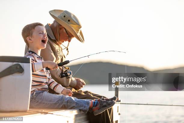 grandfather and grandson fishing at sunset in summer - multi generation family photos imagens e fotografias de stock