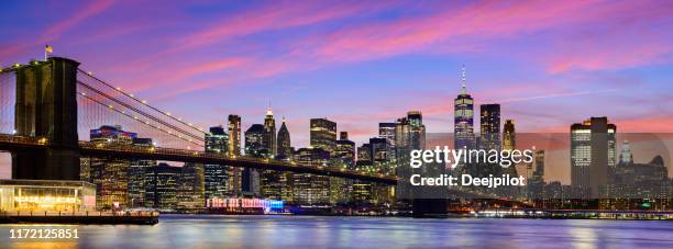 panoramic view of the manhattan city skyline and brooklyn bridge at twilight, new york, usa - new york city skyline night stock pictures, royalty-free photos & images
