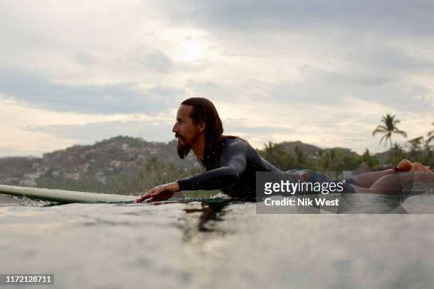 male surfer paddling out on ocean - using a paddle stock pictures, royalty-free photos & images