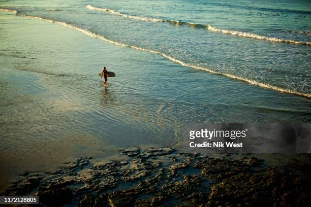 female surfer carrying surfboard in sunny ocean surf, punta de mita, nayarit, mexico - nayarit stock pictures, royalty-free photos & images