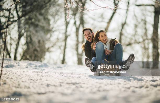 fröhliches paar mit spaß beim schlittenfahren auf einem schnee in der natur. - schlittenfahren stock-fotos und bilder