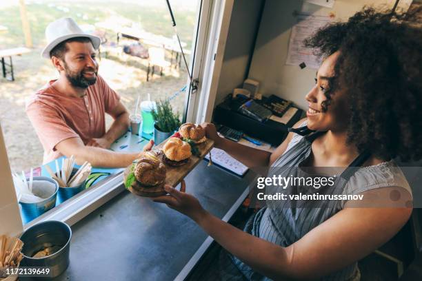 lachende afrikaanse vrouw verkopen hamburgers in food truck - food stall stockfoto's en -beelden