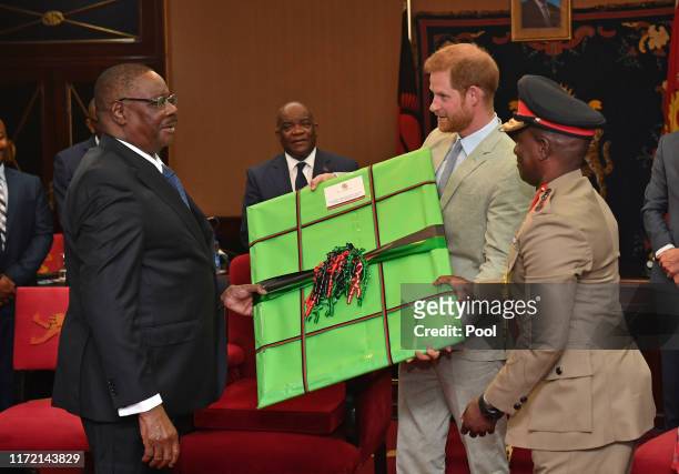 Prince Harry, Duke of Sussex receives a gift from Professor Arthur Peter Mutharika, President of the Republic of Malawi at the State House on day...