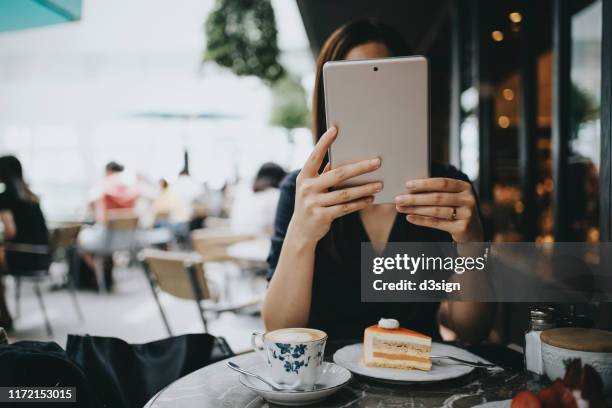 young woman using digital tablet in an outdoor cafe - obscured face phone stock pictures, royalty-free photos & images