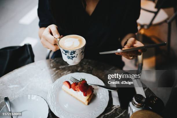 close up of busy young businesswoman working on digital tablet in an outdoor cafe - afternoon tea stock-fotos und bilder