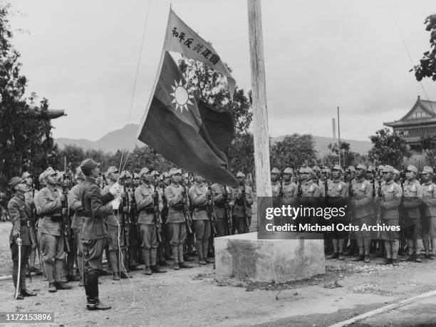 Students stand at attention as China's National Flag is hoisted on a flagpole at a military school in Nanjing under the Wang Jingwei regime, China,...