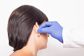 A plastic surgeon doctor examines a patient s girl s ears before performing an otoplasty surgery, close-up