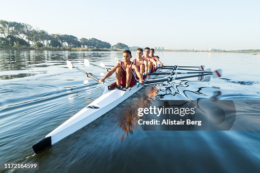 Mixed race rowing team training on a lake at dawn Mixed race rowing team training on a lake at dawn