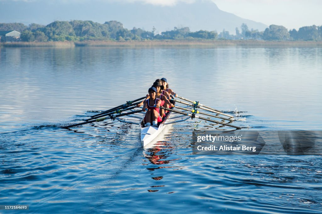 Mixed race female rowing team training on a lake