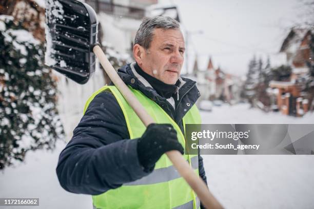 senior mann geht, um schnee zu reinigen - arbeiter winter stock-fotos und bilder