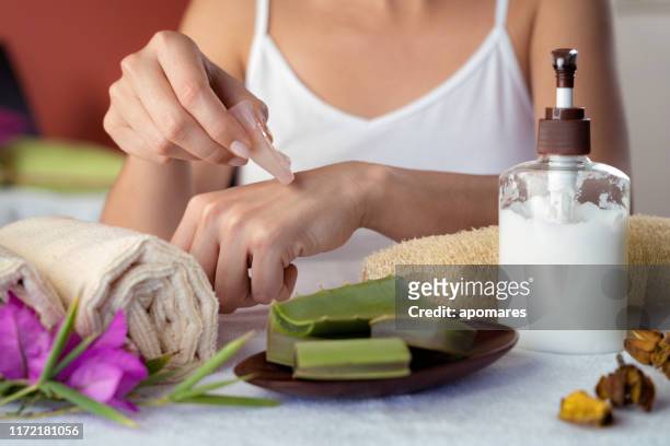 hispanic jonge vrouw hydraterende handen met aloë vera natural gel - aloe vera stockfoto's en -beelden