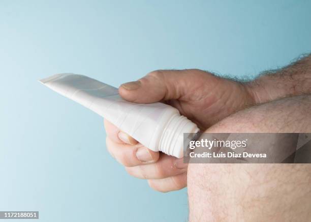 man applying cream with plastic massage tube with 3 roller ball applicator, for knee pain - applying cream stock pictures, royalty-free photos & images