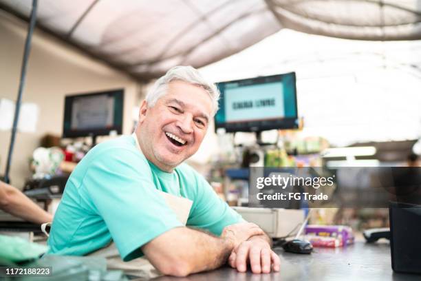 senior florist as cashier in a small flower shop - small store stock pictures, royalty-free photos & images