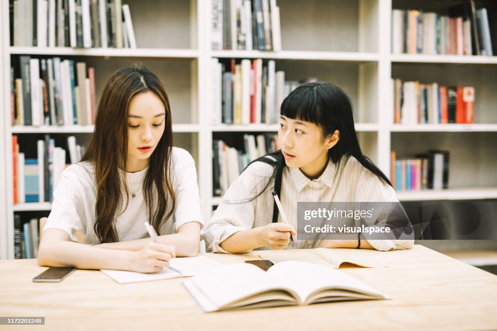 Friend Explaining Woman Explaining Friend At Desk In Library High-Res Stock Photo - Getty ...