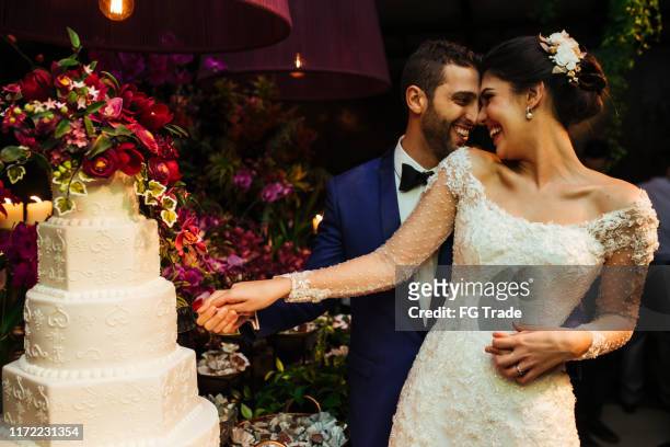 newlyweds cutting wedding cake - wedding reception stock pictures, royalty-free photos & images