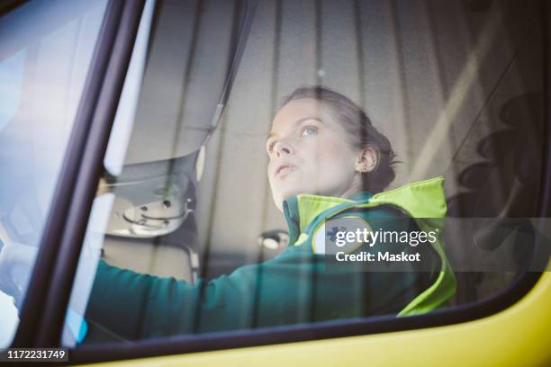 thoughtful mid adult paramedic sitting in ambulance - ambulance staff stock pictures, royalty-free photos & images