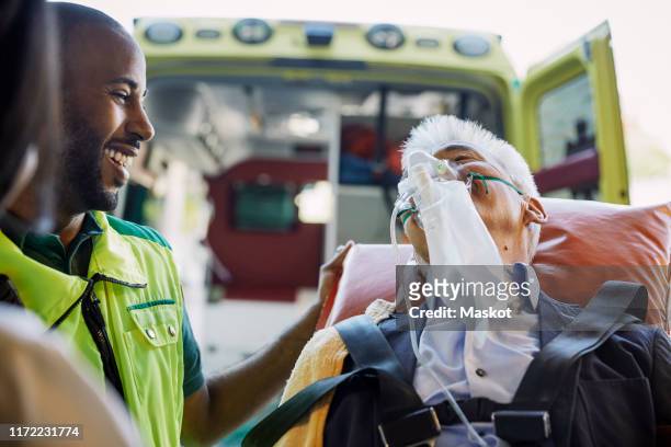 smiling male paramedic encouraging businessman against ambulance - breathing device stock pictures, royalty-free photos & images