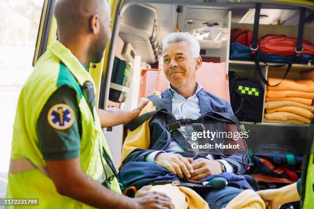 male paramedic consoling mature patient in ambulance - emergency services occupation stockfoto's en -beelden