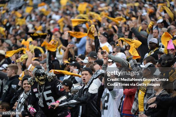 Raiders fans are surrounded by Pittsburg fans waving the terrible towel during the Oakland Raiders vs. Pittsburgh Steeler game at O.co Coliseum in...