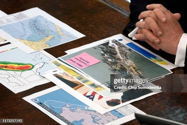 Photographs and maps sit on U.S. President Donald Trump's desk as he talks to reporters following a briefing from officials about Hurricane Dorian in...