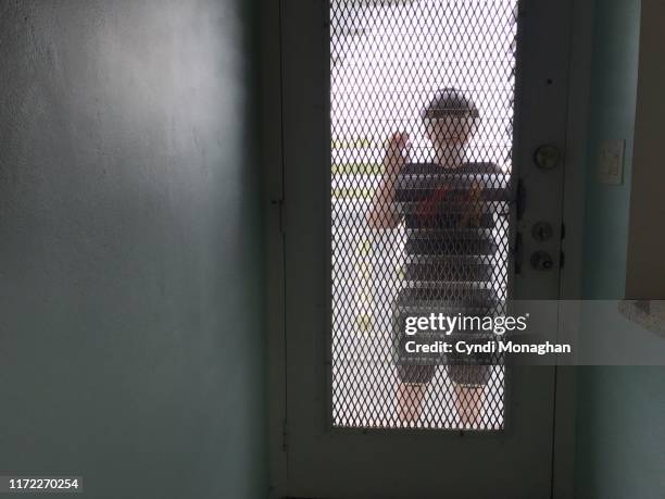 young boy peering through a translucent front door - bussare foto e immagini stock