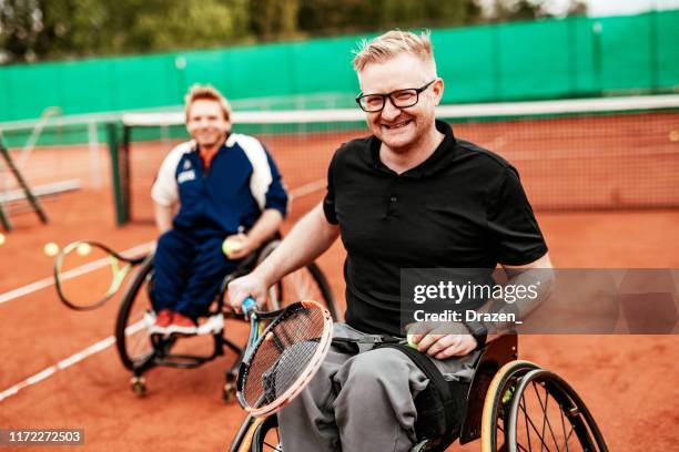 two determined mature men playing doubles in wheelchair tennis - wheelchair tennis stock pictures, royalty-free photos & images