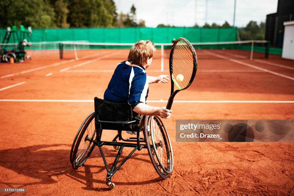 Adult man in wheelchair playing tennis
