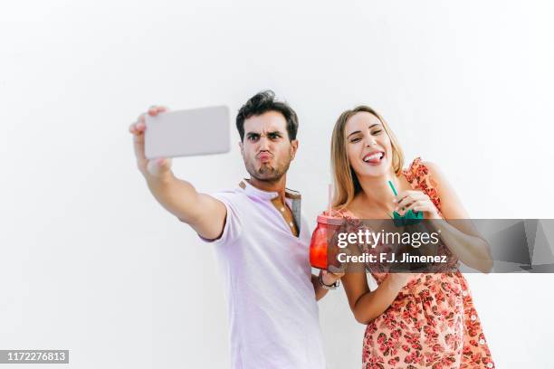 couple with cocktail taking a selfie with smart phone - taking selfie white background stockfoto's en -beelden