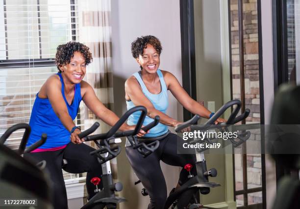 identical twins staying in shape at the gym - twin bicycle stock pictures, royalty-free photos & images