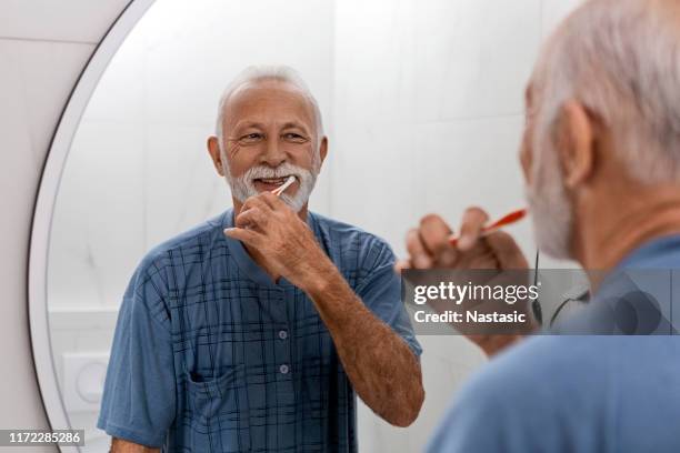 uomo anziano che mantiene la propria igiene dentale - lavarsi i denti foto e immagini stock