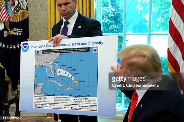 President Donald Trump references a map held by acting Homeland Security Secretary Kevin McAleenan while talking to reporters following a briefing...
