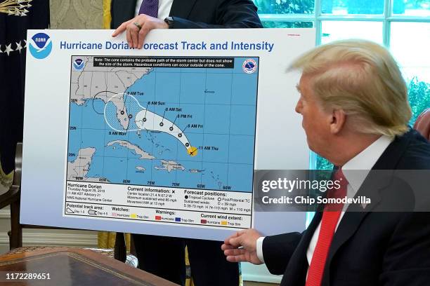 President Donald Trump references a map held by acting Homeland Security Secretary Kevin McAleenan while talking to reporters following a briefing...