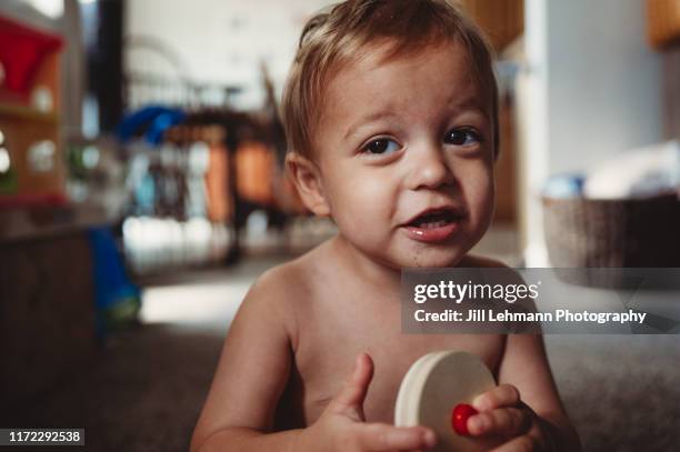 portrait of a male 2 year old toddler playing with toys in middle class home - smirking stock pictures, royalty-free photos & images