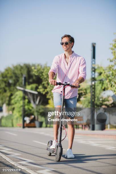 young man on electric scooter during sunny day - man on scooter stock pictures, royalty-free photos & images