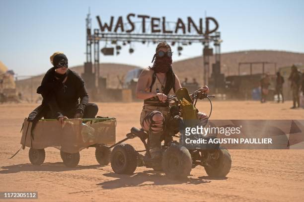 Women cruise on an ATV around the field during Wasteland Weekend festival at the Mojave desert in Edwards, California on September 28, 2019. - In...