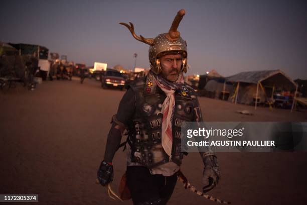 Man walks past campgrounds during Wasteland Weekend festival at the Mojave desert in Edwards, California on September 28, 2019. - In 2019 the world's...