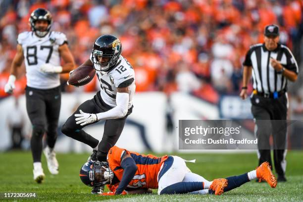 Dede Westbrook of the Jacksonville Jaguars is tripped up by DeVante Bausby of the Denver Broncos after a fourth quarter catch at Empower Field at...