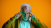 Elderly male mentalist demonstrating mind-reading power at camera, telepathy