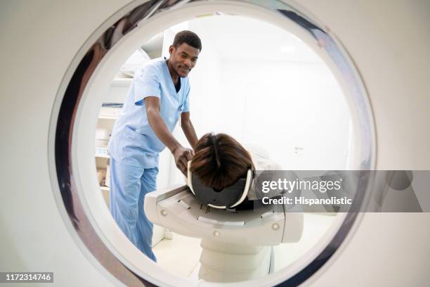 フレンドリーな黒人男性放射線科医は、笑顔のcatスキャンのための患者を準備します - mri ストックフォトと画像