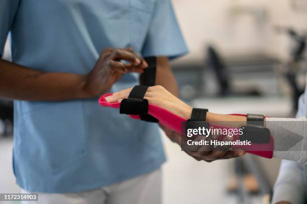 unrecognizable therapist arranging a hand brace on patient - orthopedist stock pictures, royalty-free photos & images