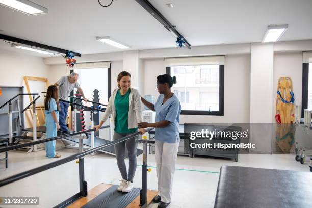 latijns-amerikaanse patiënten tijdens fysiotherapie lopen met behulp van parallelle staven - accident recovery stockfoto's en -beelden